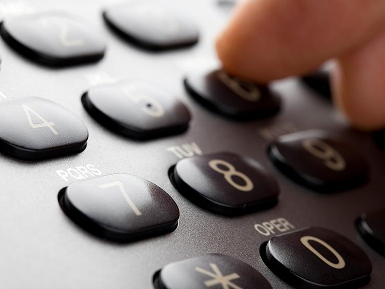 palec dłoni wciskający przyciski na&nbsp;telefonier